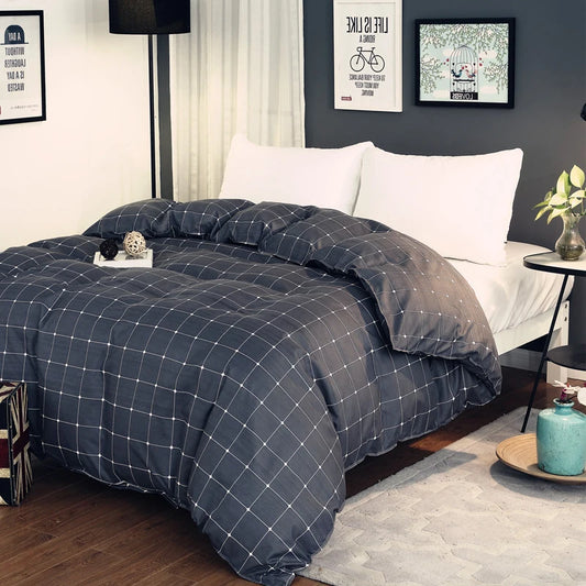 Housse de couette anthracite à motif quadrillé blanc, posée sur un lit double moderne.