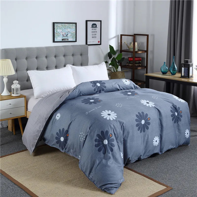 Housse de couette bleue imprimée de grandes marguerites blanches avec envers uni gris clair sur un lit double moderne.