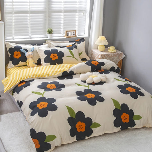 Housse de couette crème imprimée de grandes fleurs noires à cœur orange et feuilles vertes, avec envers en vichy jaune, sur un lit double moderne.