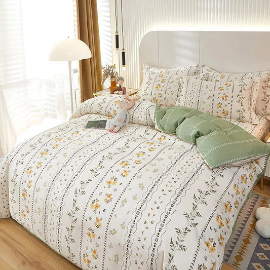 Housse de couette écru à motif floral jaune et vert, installée sur un lit dans une chambre lumineuse.