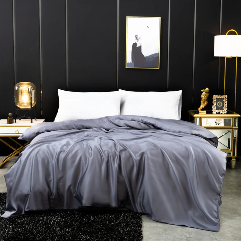 Housse de couette en soie gris perle à l’aspect satiné, drapée sur un lit moderne dans une chambre design.