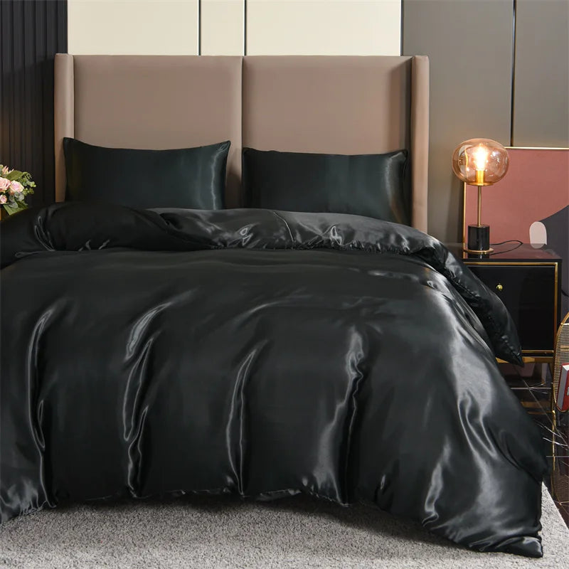 Housse de couette noire satiné lisse sur un lit avec deux taies d’oreiller assorties, dans une chambre élégante et moderne.