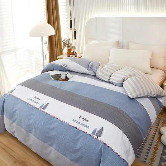 Housse de couette rayée bleu, blanc cassé et gris, motif “Bonjour – Love yourself more”, drapée sur un lit élégant.