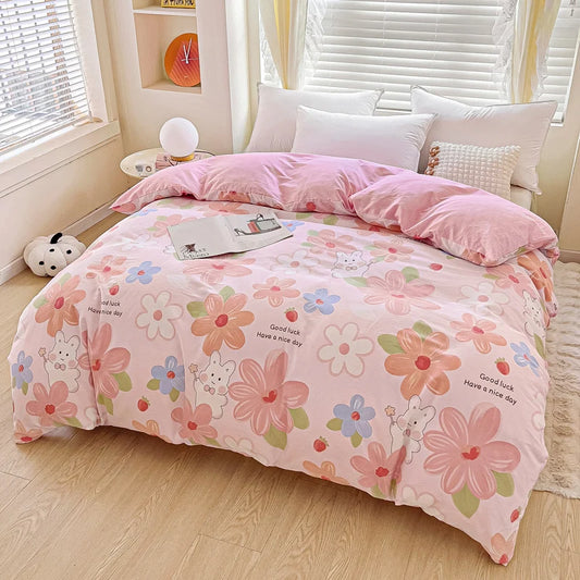 Housse de couette rose imprimée de grandes fleurs pastel et d’un lapin mignon, drapée sur un lit clair.