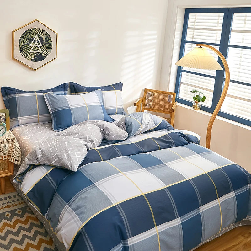Housse de couette coton motif carreaux bleu, gris et jaune, présentée sur un lit moderne, ambiance lumineuse.